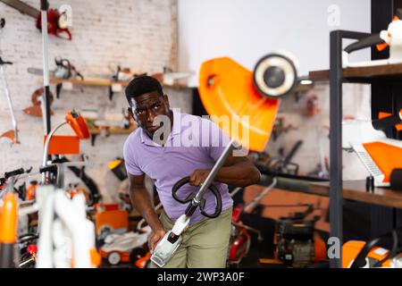 Uomo che seleziona nuovo Strimmer nel negozio di attrezzi di giardinaggio Foto Stock