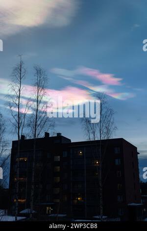 Nuvole iridescenti (nuvole arcobaleno) di sera, sopra l'edificio degli appartamenti in Finlandia. Foto Stock