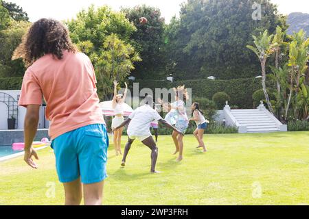 Un gruppo di amici che giocano con un pallone da calcio in un cortile soleggiato con spazio fotocopie Foto Stock