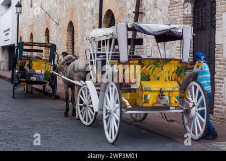 Carrozze dipinte trainate da cavalli in attesa di passeggeri nella vecchia città coloniale di Santo Domingo, Repubblica Dominicana. Patrimonio dell'umanità dell'UNESCO Foto Stock