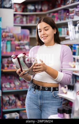 Giovane donna positiva che tiene il kit di prodotti per capelli in negozio di cosmetici Foto Stock