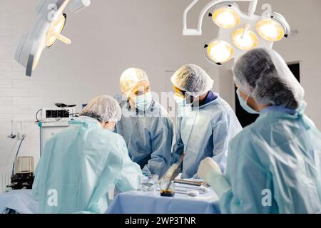 Un gruppo di medici che indossano le maschere è in piedi intorno a un tavolo. Foto Stock