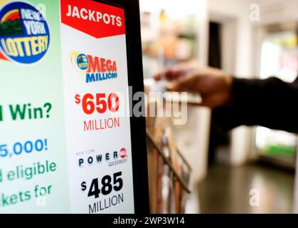 New York, Stati Uniti. 4 marzo 2024. Un cliente compra una lotteria mentre un display mostra il jackpot Mega Millions a 650 milioni di dollari e il jackpot Powerball a 485 milioni di dollari al Rockefeller Center martedì 5 marzo 2024 a New York City. Foto di John Angelillo/UPI credito: UPI/Alamy Live News Foto Stock