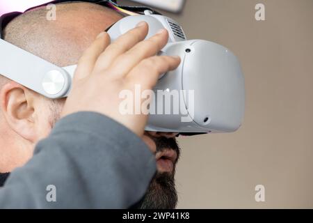 Uomo barbuto stupito che indossa occhiali per realtà virtuale. Maschio nel visore VR. Tecnologia moderna per il lavoro, l'istruzione e l'intrattenimento. Selettivo Foto Stock