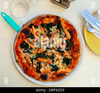 Pizza con spinaci verdi, salmone affumicato e formaggio Foto Stock