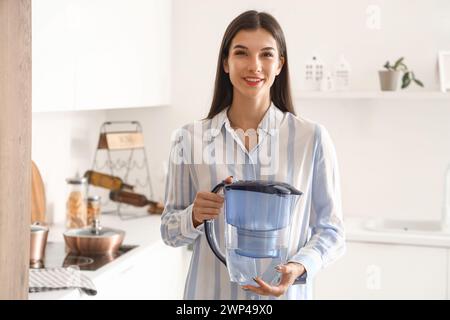 Giovane donna con caraffa del filtro dell'acqua in cucina Foto Stock