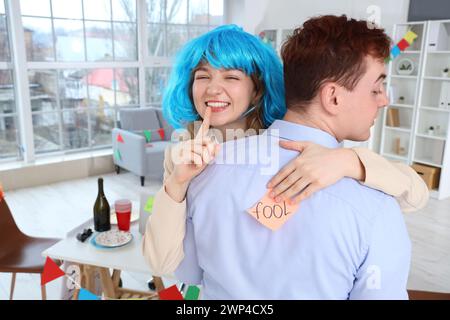 Donna d'affari che attacca carta sul ritorno in ufficio del suo collega. Festa del Fool's Day di aprile Foto Stock