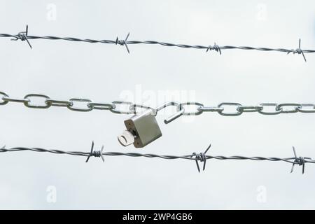 Catena con lucchetto aperto su filo spinato isolato su sfondo bianco, concetto di libertà Foto Stock