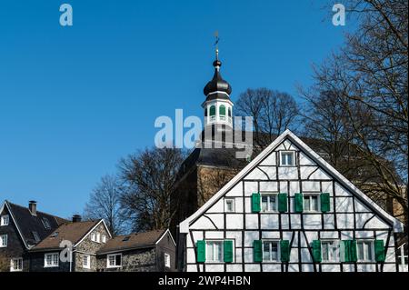 Una chiesa medievale dietro una classica casa a graticcio con tetto in ardesia, Graefrath, Solingen, Bergisches Land, Renania settentrionale-Vestfalia Foto Stock