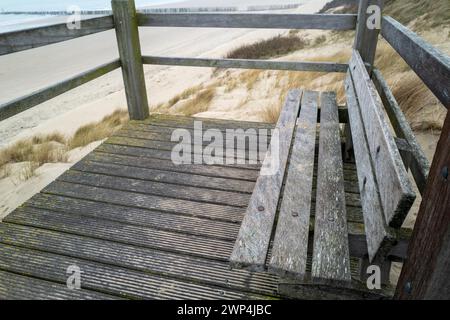 Vecchia panchina in legno su una passerella con vista sul paesaggio delle dune Foto Stock