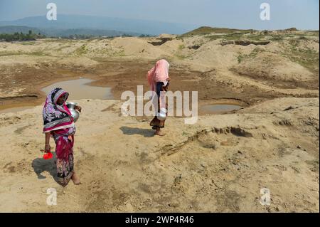 Sylhet, Bangladesh. 5 marzo 2024. 5 marzo 2024, Sylhet, Bangladesh: Due casalinghe stanno raccogliendo acqua per uso domestico da un serbatoio quasi secco nella zona di Kalairag, Bholaganj, al confine con Companiganj upazila. L'estrazione non pianificata di sabbia e pietre nella zona ha distrutto insediamenti, terreni agricoli e corpi idrici, ora l'area di Kalirag è quasi una terra desolata.il 5 marzo 2024 a Sylhet, Bangladesh. (Foto di MD Rafayat Haque Khan/ Eyepix Group/Sipa USA) credito: SIPA USA/Alamy Live News Foto Stock