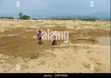 Sylhet, Bangladesh. 5 marzo 2024. 5 marzo 2024, Sylhet, Bangladesh: Due casalinghe stanno raccogliendo acqua per uso domestico da un serbatoio quasi secco nella zona di Kalairag, Bholaganj, al confine con Companiganj upazila. L'estrazione non pianificata di sabbia e pietre nella zona ha distrutto insediamenti, terreni agricoli e corpi idrici, ora l'area di Kalirag è quasi una terra desolata.il 5 marzo 2024 a Sylhet, Bangladesh. (Foto di MD Rafayat Haque Khan/ Eyepix Group/Sipa USA) credito: SIPA USA/Alamy Live News Foto Stock