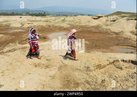 Sylhet, Bangladesh. 5 marzo 2024. 5 marzo 2024, Sylhet, Bangladesh: Due casalinghe stanno raccogliendo acqua per uso domestico da un serbatoio quasi secco nella zona di Kalairag, Bholaganj, al confine con Companiganj upazila. L'estrazione non pianificata di sabbia e pietre nella zona ha distrutto insediamenti, terreni agricoli e corpi idrici, ora l'area di Kalirag è quasi una terra desolata.il 5 marzo 2024 a Sylhet, Bangladesh. (Foto di MD Rafayat Haque Khan/ Eyepix Group/Sipa USA) credito: SIPA USA/Alamy Live News Foto Stock