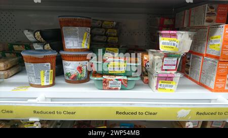 Scaffale del supermercato con prodotti alimentari da ridurre a pulire nel supermercato Tesco, cibo di etichetta gialla Foto Stock