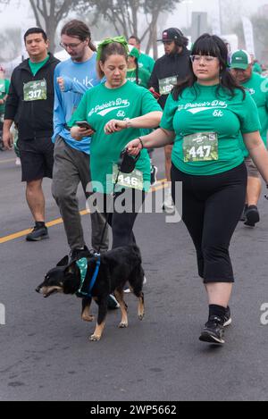 Folla di persone in magliette verdi, alcune con telefoni cellulari, durante St. Patrick's Day Run & Walk Foto Stock