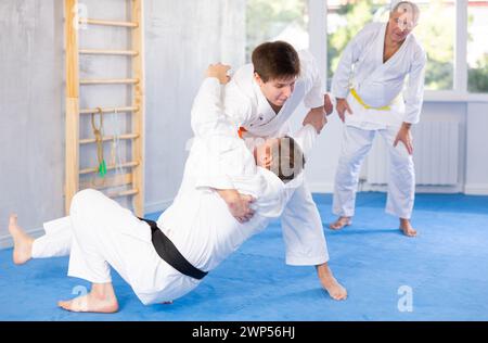 Gli uomini si allenano per lanciare sul tappeto sotto la guida del judo coach Foto Stock