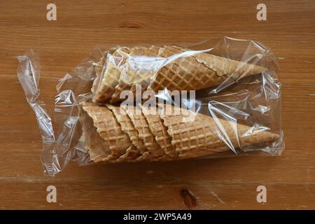 coni per cialde in una confezione di plastica su un tavolo di legno, pronti per essere ripieni di delizioso gelato Foto Stock