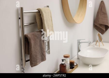 Portasciugamani riscaldato con asciugamani marroni in bagno Foto Stock