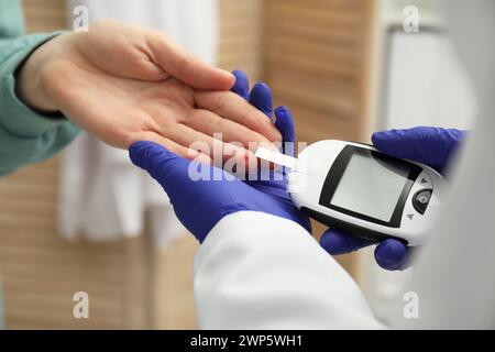 Diabete. Medico che controlla il livello di zucchero nel sangue del paziente con il glucometro in clinica, primo piano Foto Stock