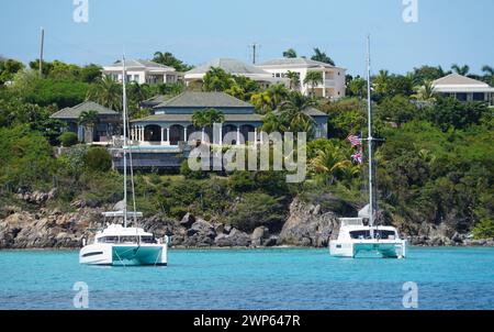 St Thomas, Isole Vergini americane - 21 febbraio 2024 - la vista del palazzo sul lungomare sulla collina rocciosa e yacht privato sulla baia Foto Stock