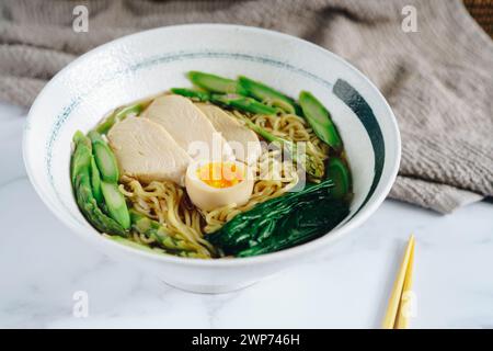 Una ciotola di ramen con pollo, asparagi e uovo Foto Stock