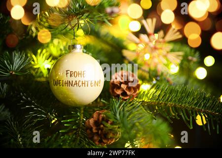 FOTOMONTAGE, Weihnachtskugel mit Aufschrift Frohe Weihnachten hängt an einem Weihnachtsbaum Foto Stock