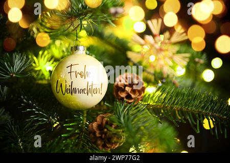 FOTOMONTAGE, Weihnachtskugel mit Aufschrift Frohe Weihnachten hängt an einem Weihnachtsbaum Foto Stock