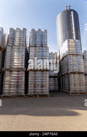 Grandi quantità di fusti di birra in alluminio impilati l'uno sull'altro con tavolozze euro e avvolti con fogli di vinile. La birra pronta per la spedizione è una bottiglia Foto Stock