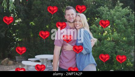 Immagine di palloncini cardiaci sopra una felice coppia caucasica in giardino Foto Stock
