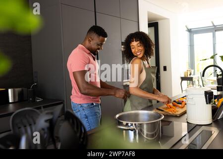 Coppia birazziale che cucina insieme in una cucina moderna a casa Foto Stock