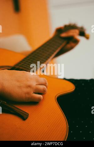 Donna senza volto che suona una vecchia chitarra acustica classica. Le mani del chitarrista in primo piano. Comporre una composizione musicale, fare musica. Colori vintage. Foto Stock