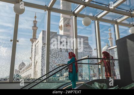 Donne sulla scala mobile Abu Dhabi Emirati Arabi Uniti. Donne vestite in modo tradizionale nel centro commerciale su scala mobile. Donne arabe che fanno shopping al coperto nel centro commerciale - gennaio 29,20 Foto Stock