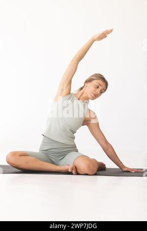 La giovane donna caucasica pratica yoga in un ambiente interno sereno con spazio fotocopie Foto Stock
