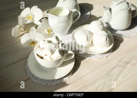 Colazione primaverile con marshmallow, caffè e latte. Appiattire con cibo e fiori di colore bianco Foto Stock