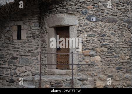 Dettaglio dell'ingresso alla prigione reale di Llivia o Livia nei Pirenei del 1834. Facciata in pietra e una vecchia porta in legno rinforzato. Foto Stock