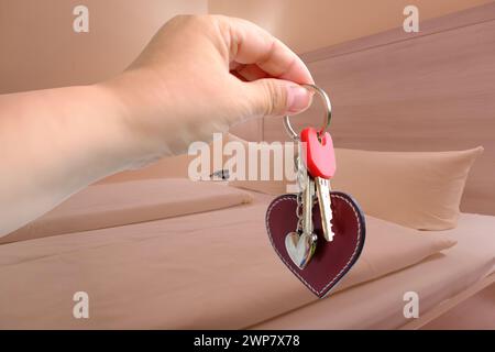 Camera da letto dell'hotel con letto matrimoniale ben fatto ricoperto di lenzuola bianche pulite, chiavi della camera per le mani femminili, che mostrano comfort e relax, servizio dell'hotel Foto Stock