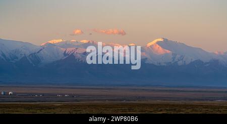 Panorama paesaggistico sulla catena montuosa Trans-Alay innevata e sul picco Lenin all'alba con alpenglow, Sary Tash, Kirghizistan Foto Stock