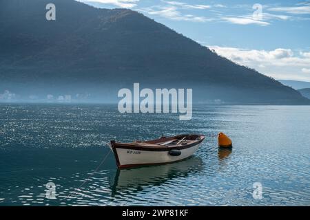 Una piccola barca situata tra le montagne del mare Adriatico. Perast, Montenegro Foto Stock