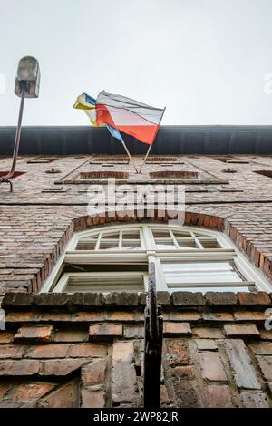 Bandiera polacca e Ucraina che sventolano insieme su una casa di mattoni a Katowice Nikiszowiec, Polonia meridionale Foto Stock