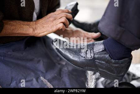 Strada, polacco o mani di uomo con scarpe in servizio di pulizia in città per brillare con cera, commercio e lavoro. Primo piano, cliente o persona con spazzolatura Foto Stock