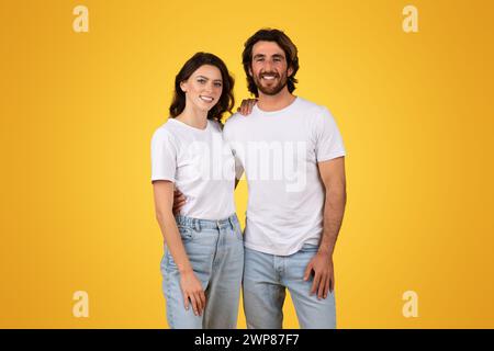 Giovane coppia sorridente in piedi insieme indossando t-shirt bianche e jeans blu Foto Stock