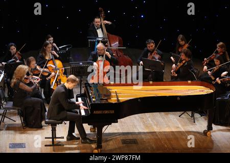 IVANO-FRANKIVSK, UCRAINA - 3 MARZO 2024 - il pianista di Leopoli Rostyslav Fedyna, accompagnato dalla Harmonia Nobile Academic Chamber Orchestra, si esibisce durante la serata di recital per pianoforte nell'ambito del festival musicale professionale Primavera 2024 di Prykarpattia sul palco della Filarmonica regionale Iryna Malaniuk Ivano-Frankivsk, Ivano-Frankivsk, Ucraina occidentale. Foto Stock