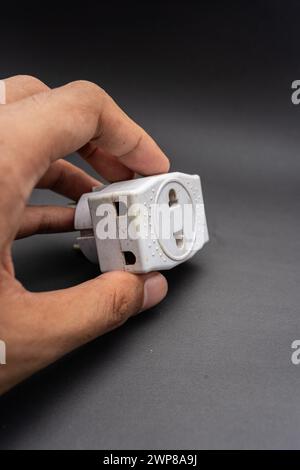 Rubinetto di uscita triplo usato sporco. Adattatore di energia elettrica utilizzato per dividere la presa utilizzata per i viaggi. Adattatore elettrico isolato su sfondo nero. Foto Stock