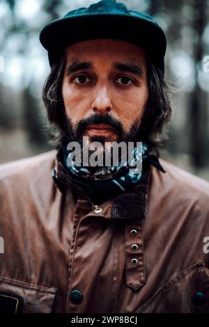 Una foto verticale di un uomo di mezza età con un'elegante giacca e cappuccio in pelle che guarda nella fotocamera Foto Stock