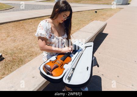 Donna di strada latina che mette il violino nel suo caso dopo aver fatto arte e suonato il violino. Foto Stock