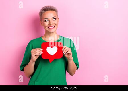 Ritratto di una bella signora con le mani in mano come una carta di carta con logo sembra uno spazio vuoto isolato su sfondo rosa Foto Stock