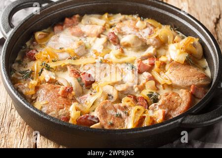 Cremosi medaglioni di filetto di maiale con cipolle, pancetta e funghi da vicino sulla teglia sul tavolo. Orizzontale Foto Stock