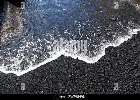 Le onde del mare arrivano sulla spiaggia di sabbia vulcanica nera di El golfo, Lanzarote, Isole Canarie, spagna Foto Stock