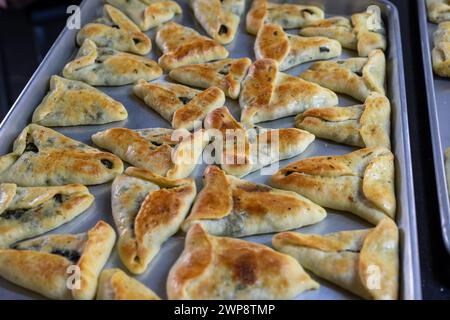 pasticcini ripieni al forno su sfondo in marmo nero pronti per essere serviti e spostati dal vassoio di alluminio alle ciotole sul tavolo della cena o nella borsa per bambini Foto Stock