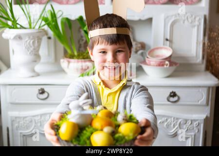 3 marzo 2024: Bambino che tiene in mano un nido di Pasqua fatto in casa con muschio e uova di Pasqua gialle. Immagine simbolica di una caccia all'uovo *** Kleiner Junge hält ein selbstgemachtes Osternest mit Moos und gelben Ostereiern in der hand. Symbolbild Eiersuche Foto Stock